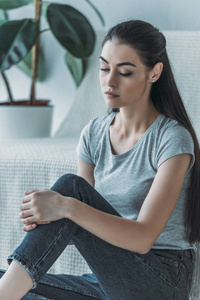 美丽的年轻悲伤的女人坐在家里