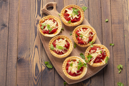 迷你比萨与意大利香肠, 西红柿和奶酪在木质的背景。美味的开胃菜, tartlet