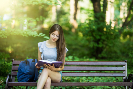女学生坐在长凳和读书书