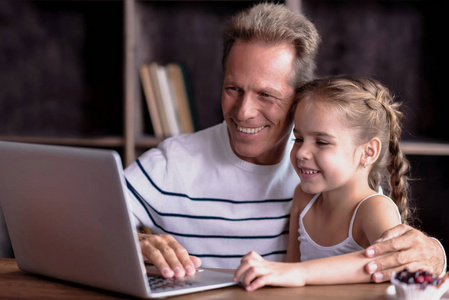 女孩与她的祖父坐在笔记本电脑前