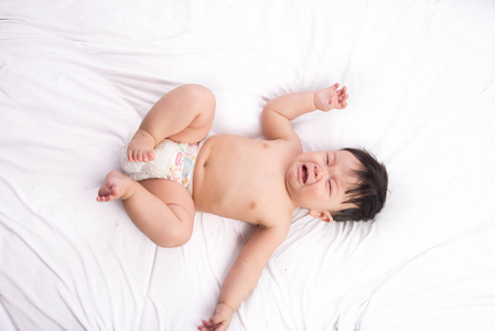 可爱的小亚洲男孩 6 个月大的白色的床上的肖像