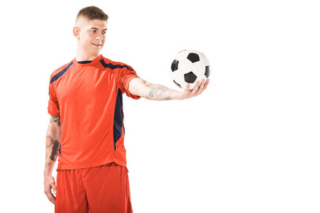 微笑的年轻足球运动员看着球在手上孤立的白色