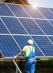在钢平台上安装的高蓝色外部太阳能电池板光电系统的工人向后看。可再生生态绿色能源生产, 做好工作理念