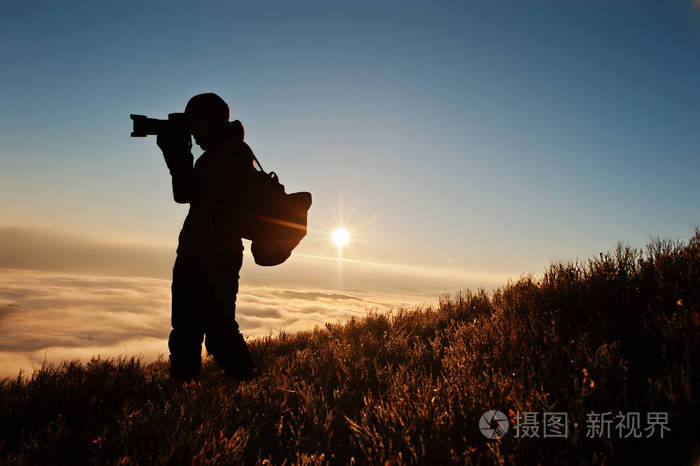 男子摄影师用相机上的手背景钼的剪影