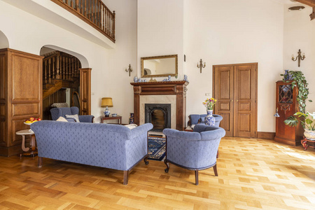 真正的照片, 蓝色的沙发和椅子在一个优雅的客厅内部与木制家具和经典壁炉
