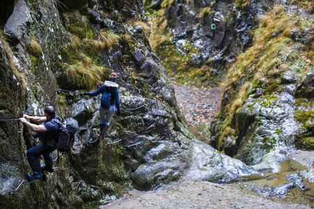 夫妇的徒步旅行者爬上安全电缆在峡谷上面