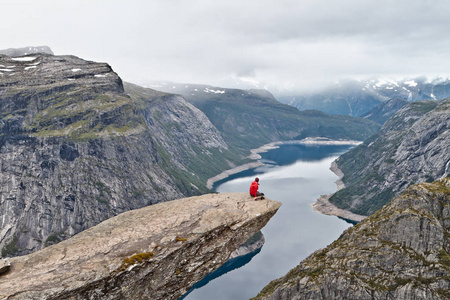 男人用相机 Trolltunga 岩 巨魔的舌头岩 会议席上，看着挪威山风景