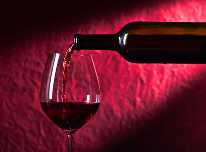 瓶子和杯子在深色背景上的红酒