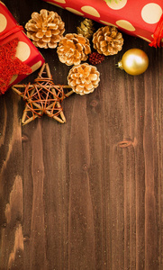 圣诞节和元旦节日的装饰, 金球, 金色的冷杉锥和木星与两个礼物包裹在红色的纸与金色圆圈在棕色木头背景。平躺着。从上面看。复制文本