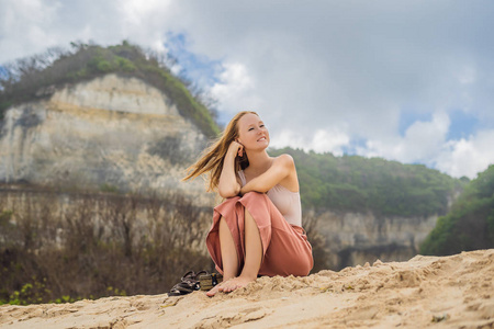 年轻的女性旅行者休息在沙滩上在多风的天气在惊人的梅拉斯蒂海滩, 巴厘岛, 印度尼西亚