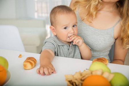 这孩子在妈妈手里吃水果早餐。