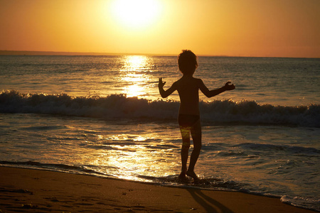 在日落时在沙滩上玩的男孩