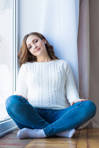 孕妇在家里靠近窗口的白色毛衣和蓝色牛仔裤