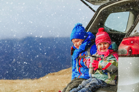 小男孩和女孩乘汽车在冬天山