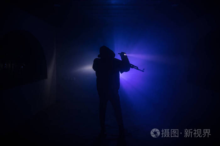有突击步枪的人的剪影准备攻击黑暗的色调雾蒙蒙的背景或拿着枪的危险