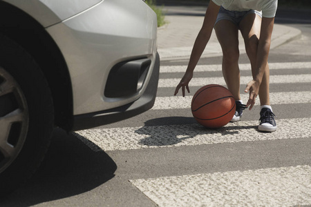 在汽车旁边的人行横道上带球的孩子特写镜头