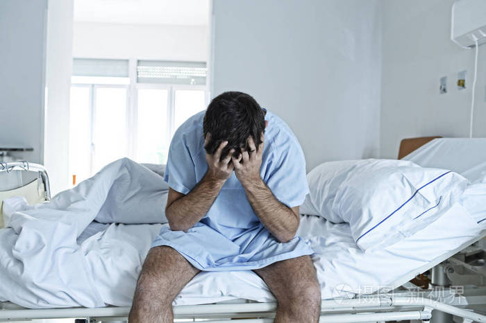 绝望的男人坐在医院床上独自伤心和破坏病临床
