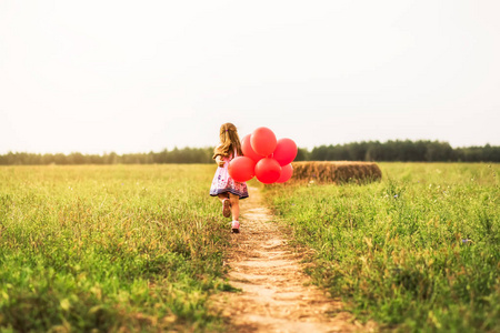 女孩在自然界中与红色气球一起奔跑