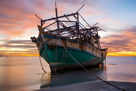 渔民船残骸漂浮在海水上, 美妙的戏剧性五颜六色的暮光之云在岛上的背景