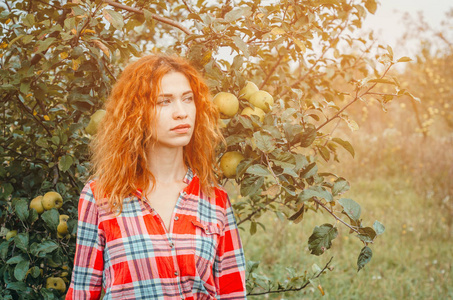 一个年轻女子在一个废弃的杂草丛生的苹果的秋天画像