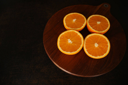 新鲜多汁的橙子切成两半在棕色的木头背景