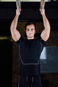 年轻健壮的肌肉男人使用体操环的肖像