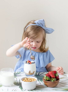 小高加索金发女孩吃健康的早餐在家里牛奶浆果草莓蓝莓希腊酸奶与麦片饮食维生素夏季食品概念