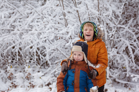 两个小孩，男孩兄弟在降雪期间在户外玩。积极的休闲活动，与孩子在天冷的冬天