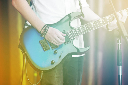 摇滚明星特写电吉他演奏的舞台上。一件白衬衫男吉他手