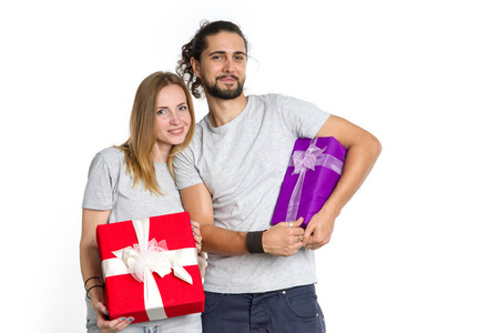 快乐的夫妇在他们手中的礼物在光背景的年轻人。节日气氛中的男人和女人新年, 圣诞节, 情人节