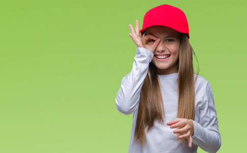 年轻美丽的女孩戴着红色的帽子孤立的背景做确定的手势与手微笑, 眼睛通过手指看与快乐的脸