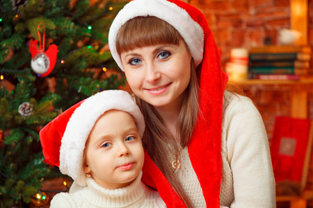 母亲和女儿在圣诞老人帽的画像。圣诞快乐