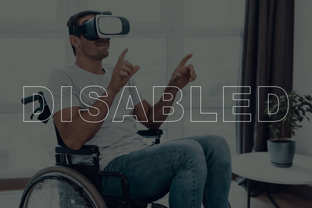 坐在轮椅上的残疾人。戴着虚拟现实眼镜的男人。人是指手的手势。人在微笑。成人褐发女郎男子. 人位于客厅。虚拟技术