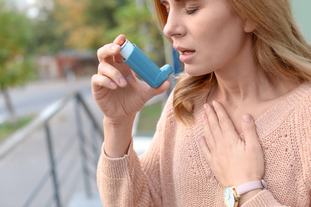 妇女使用哮喘吸入器户外, 特写镜头。保健