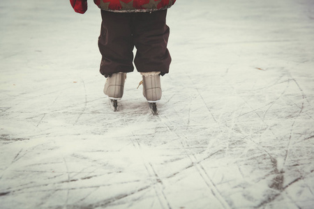 学习在冬天在冰上滑冰的孩子脚