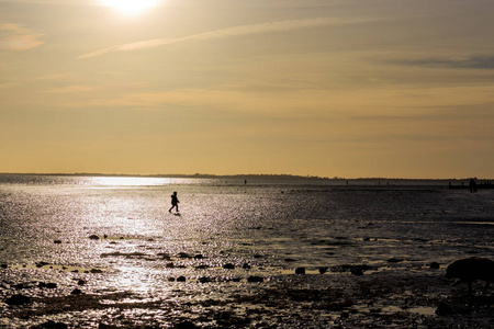 在英国日落海滩上玩耍的一个小孩的剪影