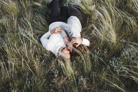 躺在羽毛草中的快乐的年轻有爱心的夫妇