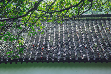 中国传统住宅的建筑细节, 绿色树木下的黑色瓷砖屋顶, 在杭州, 中国