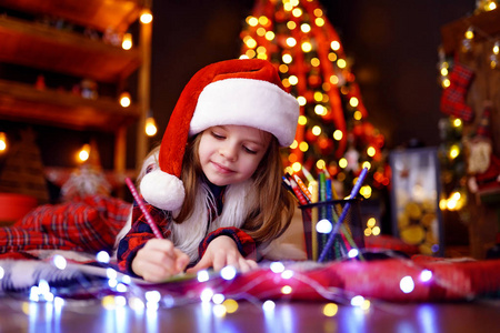 风趣的女孩在圣诞老人帽子给圣诞老人写封信
