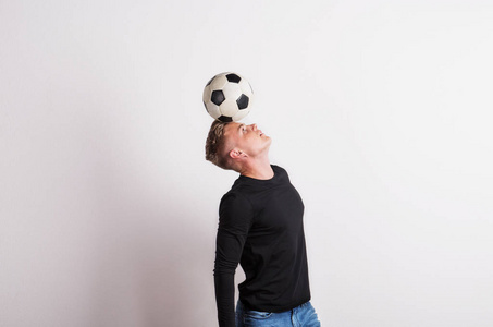一个头上有足球的年轻人在演播室里的肖像。复制空间