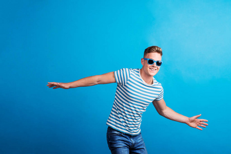 一个戴着蓝色太阳镜的年轻人站在演播室里玩得很开心