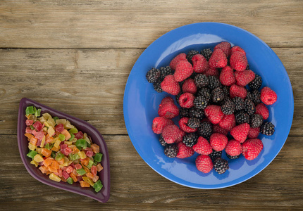 盘子里的黑莓和覆盆子。在木背景的黑莓和覆盆子。素食