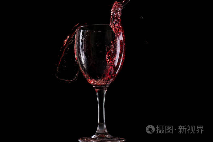 红酒掉进杯子里, 在黑色的背景上飞溅
