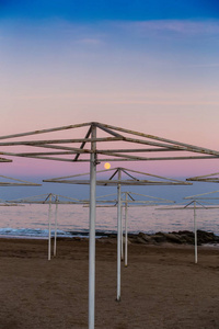 日落时在空旷的海滩上的雨伞。赛季结束