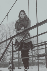 黑色和白色，俄罗斯美女穿着羊皮大衣站在雪地里桥上