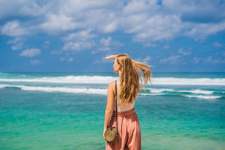 年轻女子享受天气在惊人的梅拉斯蒂海滩与绿松石水, 巴厘岛, 印度尼西亚