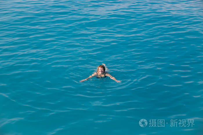 在蓝色的水中游泳的活跃高级女人