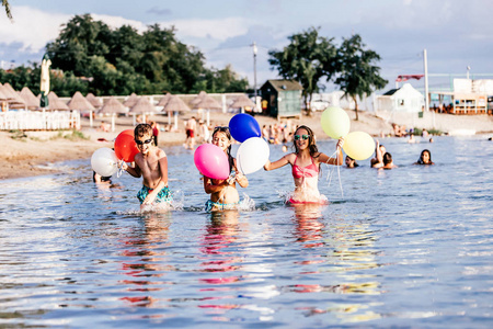 快乐的孩子们在海里玩气球。孩子们在户外玩得很开心。暑假和健康的生活方式概念