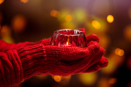 举行圣诞蜡烛在温暖的手套的妇女