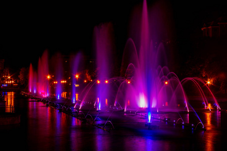 在远东城市哈巴罗夫斯克, 发光的五颜六色的照明喷泉。夏季结束时的秋季歌唱喷泉表演